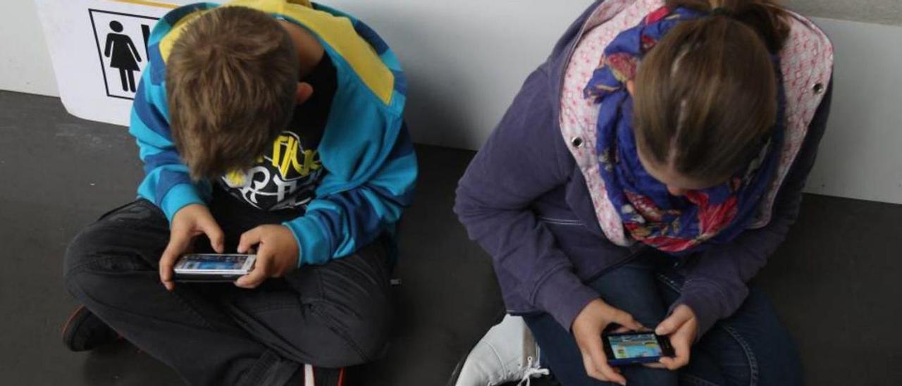 Dos niños concentrados en el móvil.