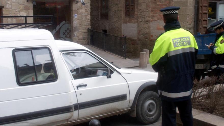 Dos agents de la Policia Local del Solsona multant un vehicle mal estacionat.