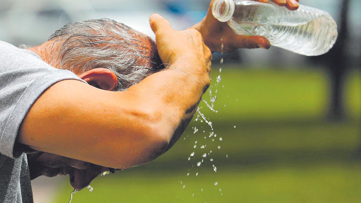 Un hombre se refresca con una botella de agua.