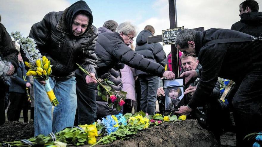 Una mujer coloca flores en la tumba de su hijo de 38 años muerto en los combates de la ciudad de Bajmut.