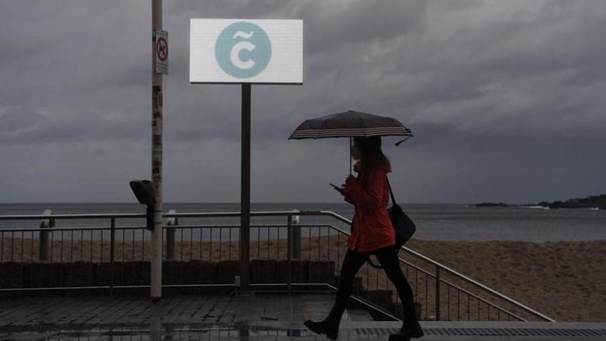 Una mujer con un paraguas en el paseo marítimo de A Coruña.