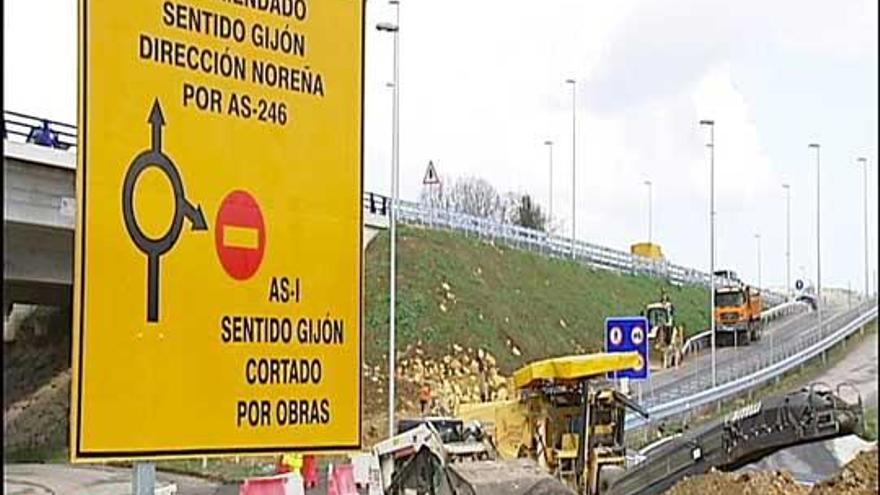 Máquinas trabajando en el carril cortado hacia Gijón, con la señal de obras en primer plano.