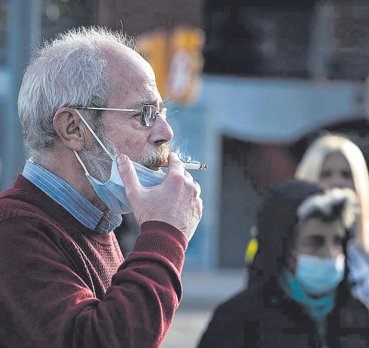 Un hombre fumando un cigarrillo en una calle.
