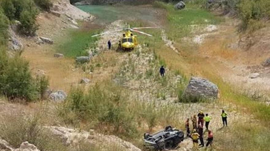 El coche volcado y el helicóptero de rescate a pocos metros del agua del Pantano de Crevillent.