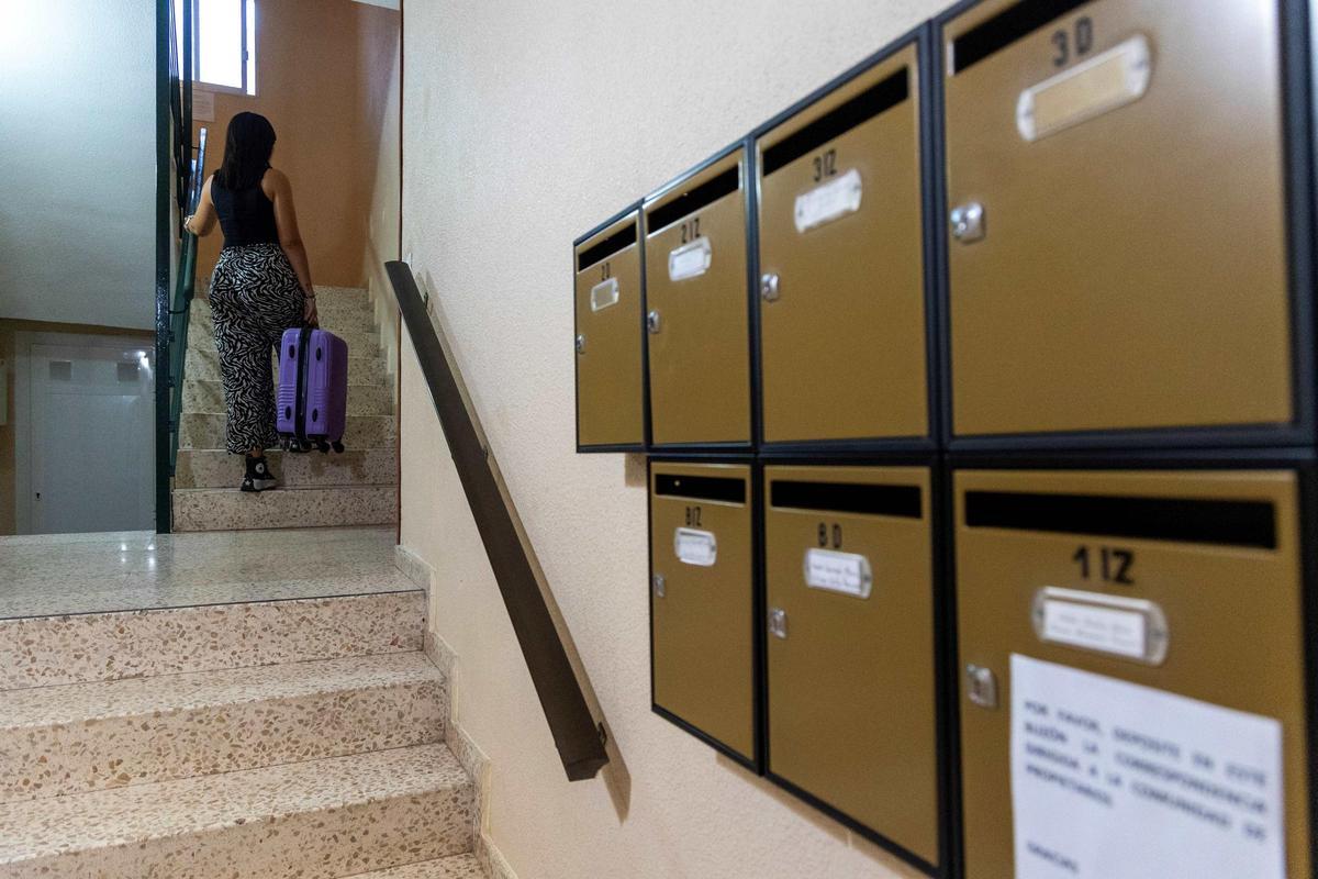 Una joven subiendo las escaleras de una casa con las maletas.