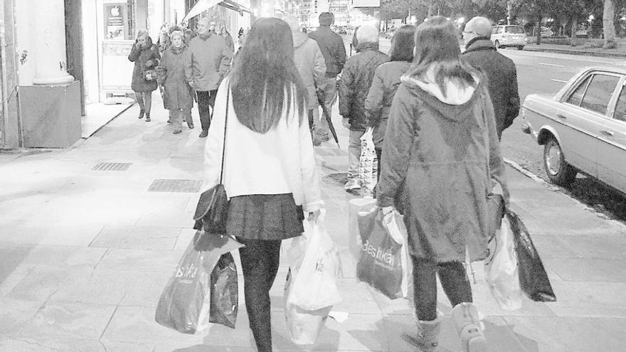 Dos jóvenes con bolsas, tras realizar unas compras. // Fran Queruga