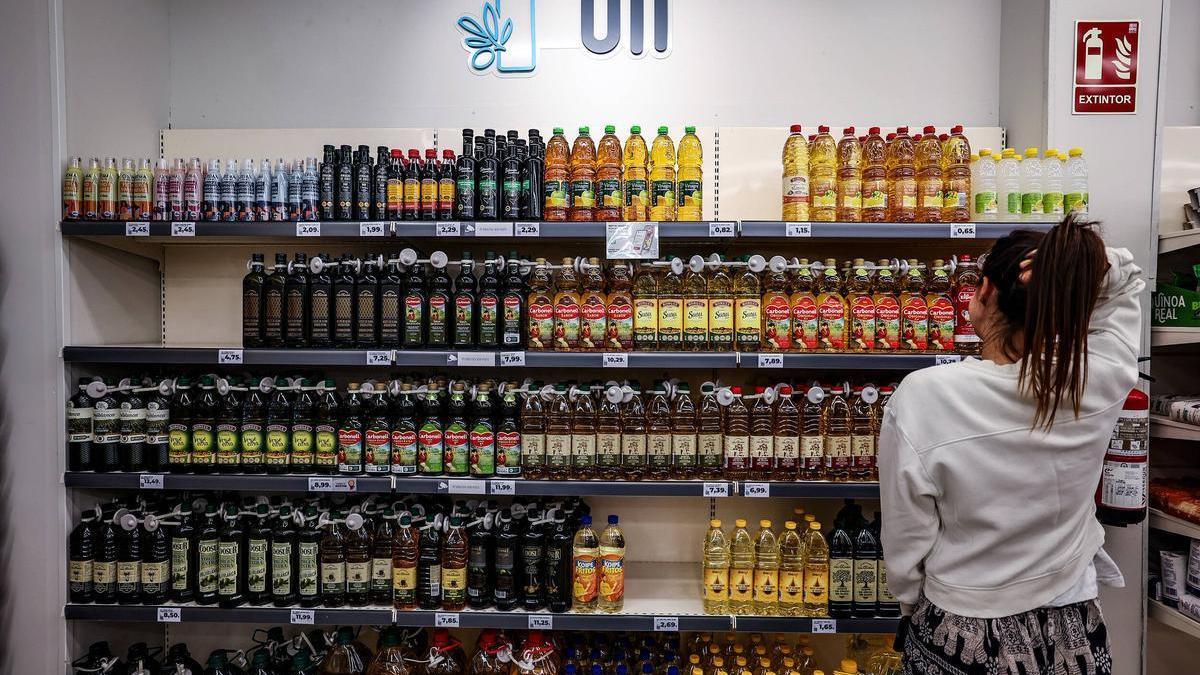 Una chica observa la estantería de los aceites en un supermercado.