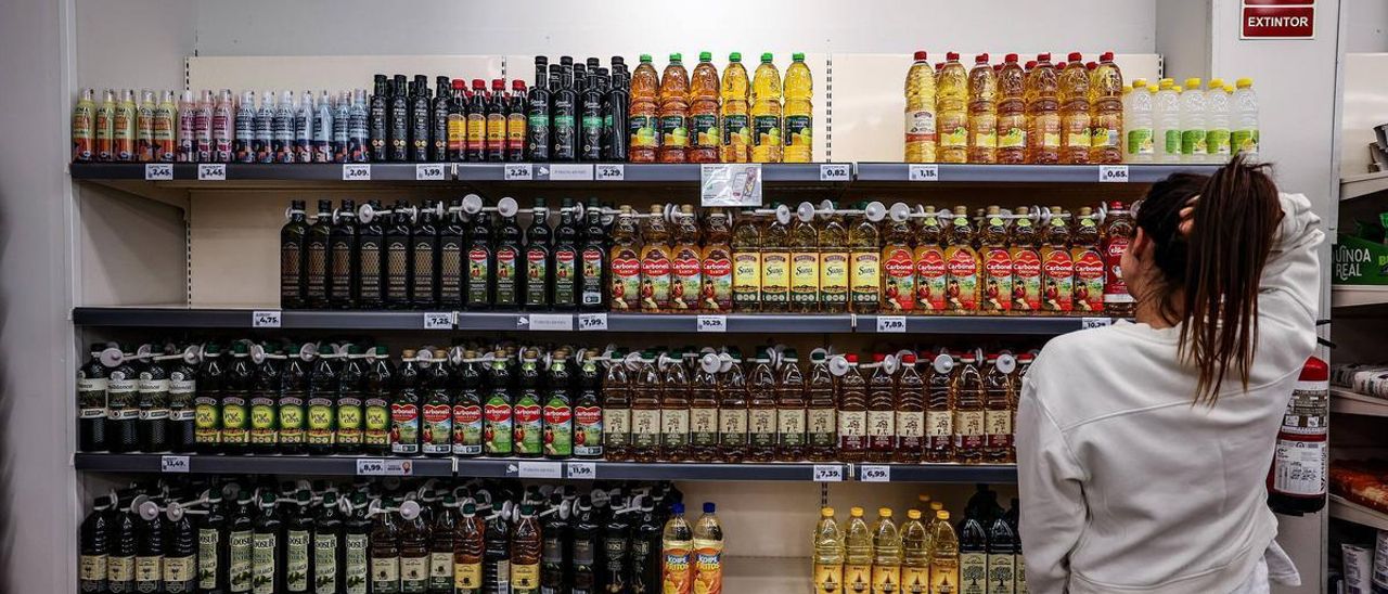 Una joven observa la estantería de los aceites en un supermercado.