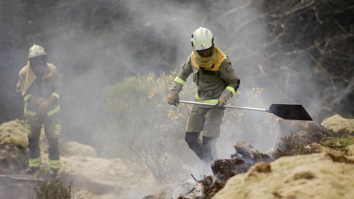 Dos brigadistas trabajan para extinguir las llamas en Lugo.