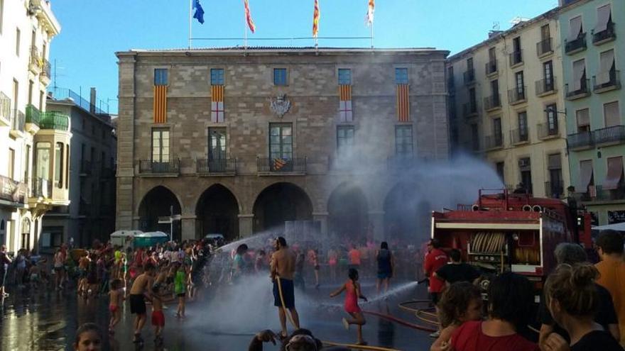 Voluntaris ruixant els petits a la plaça Major.