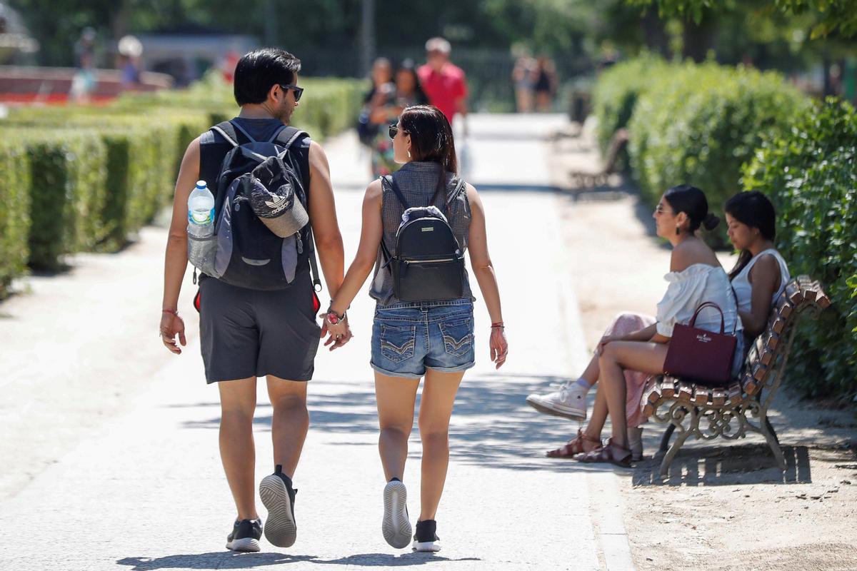 Dos jóvenes pasean por un parque de Madrid. 