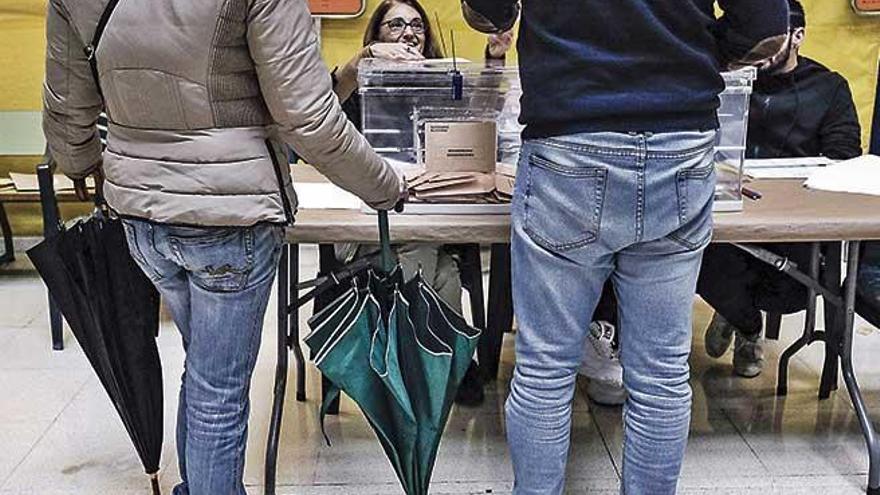 Una pareja acude a votar el domingo con paragÃ¼as por la lluvia.