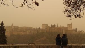 Dos personas observan la Alhambra de Granada desde el Mirador de San Nicolás durante el episodio de calima del pasado mes de marzo, uno de los más intensos registrados en las últimas décadas.