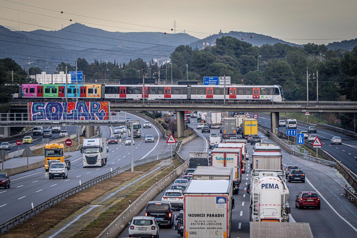 La AP-7, a la altura de Sant Cugat, llena de camiones, en el momento en el que la autopista se cruza con la línea de FGC que va a Sabadell