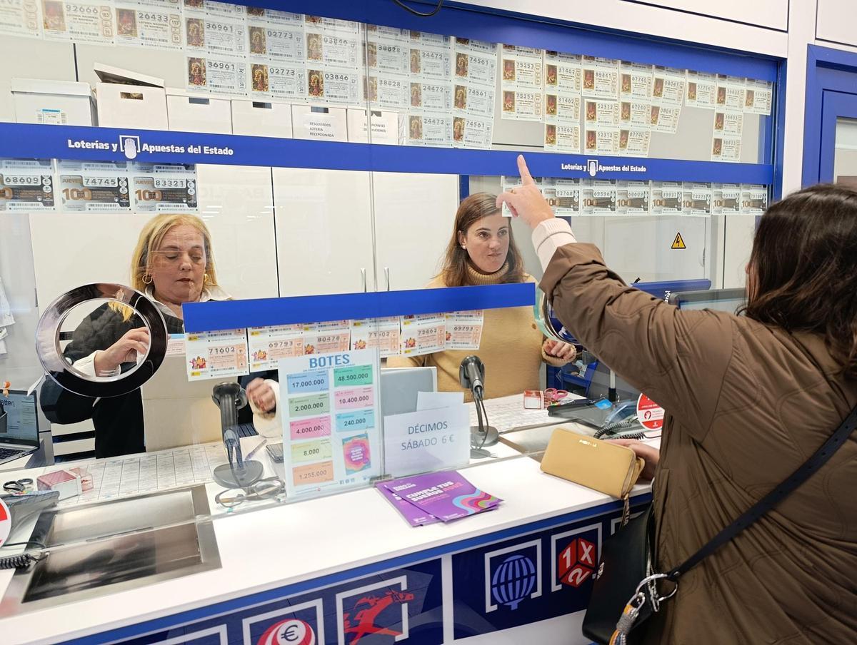 Por la izquierda, Virginia Corujo y Cristina Riestra atienden a una clienta en la Administración de Lotería número 1 de Pola de Siero.