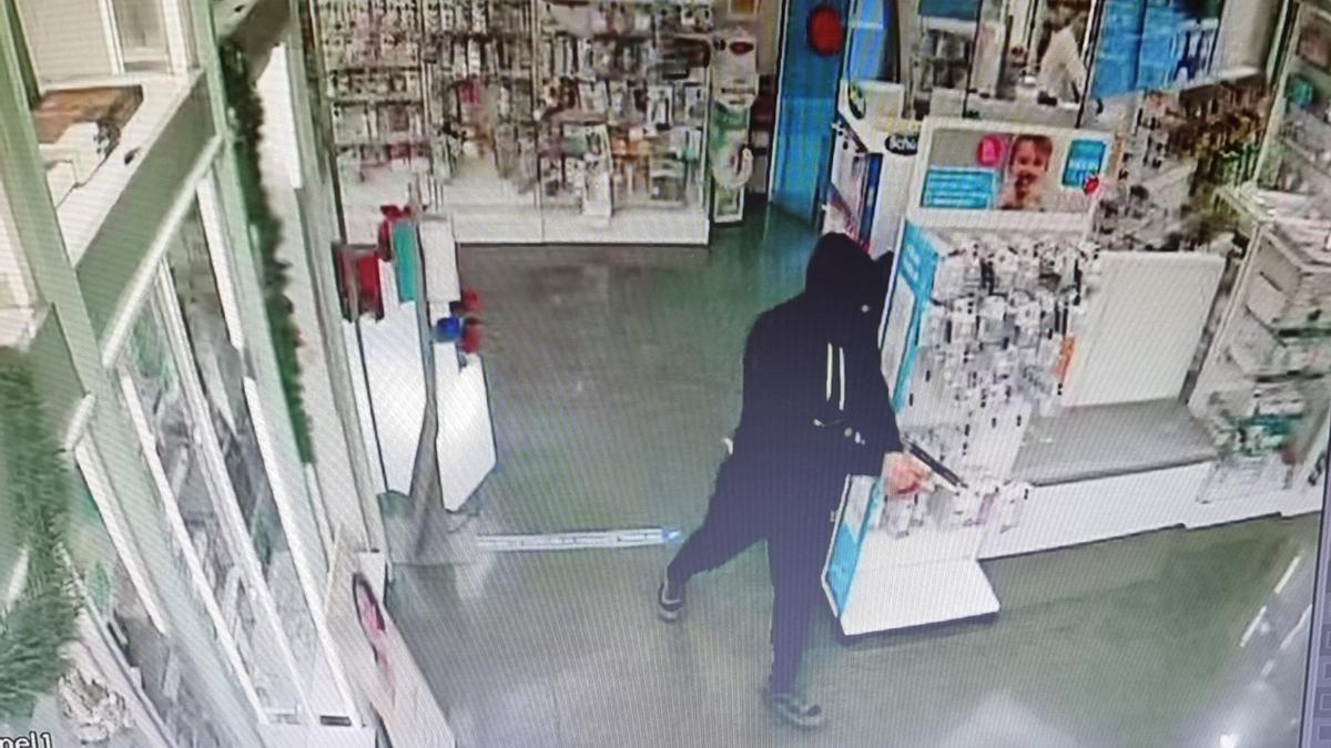 Las cámaras de seguridad de la farmacia captaron al ladrón, encapuchado y pistola en mano.