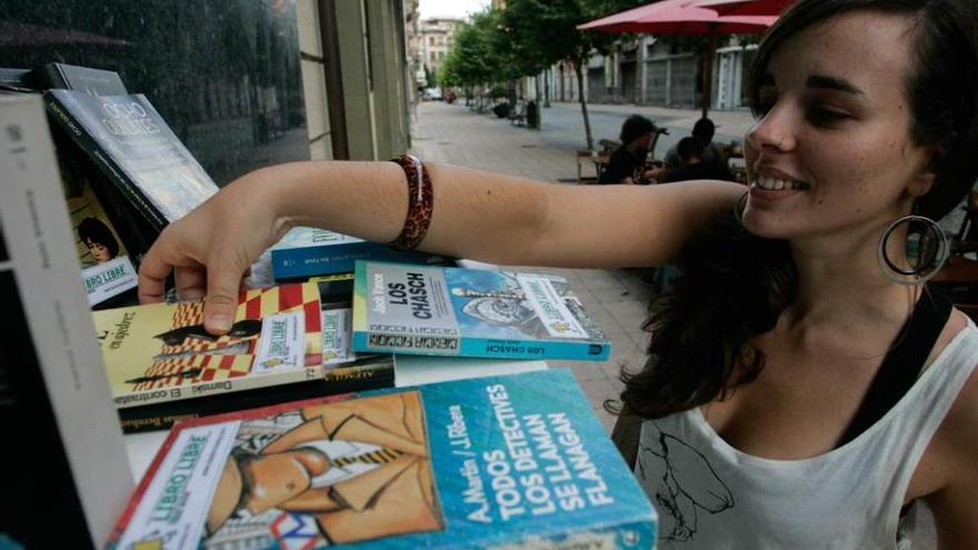 Una chica ojea los títulos de los libros a disposición del público en un local avilesino que colabora con el &quot;bookcrossing&quot;.