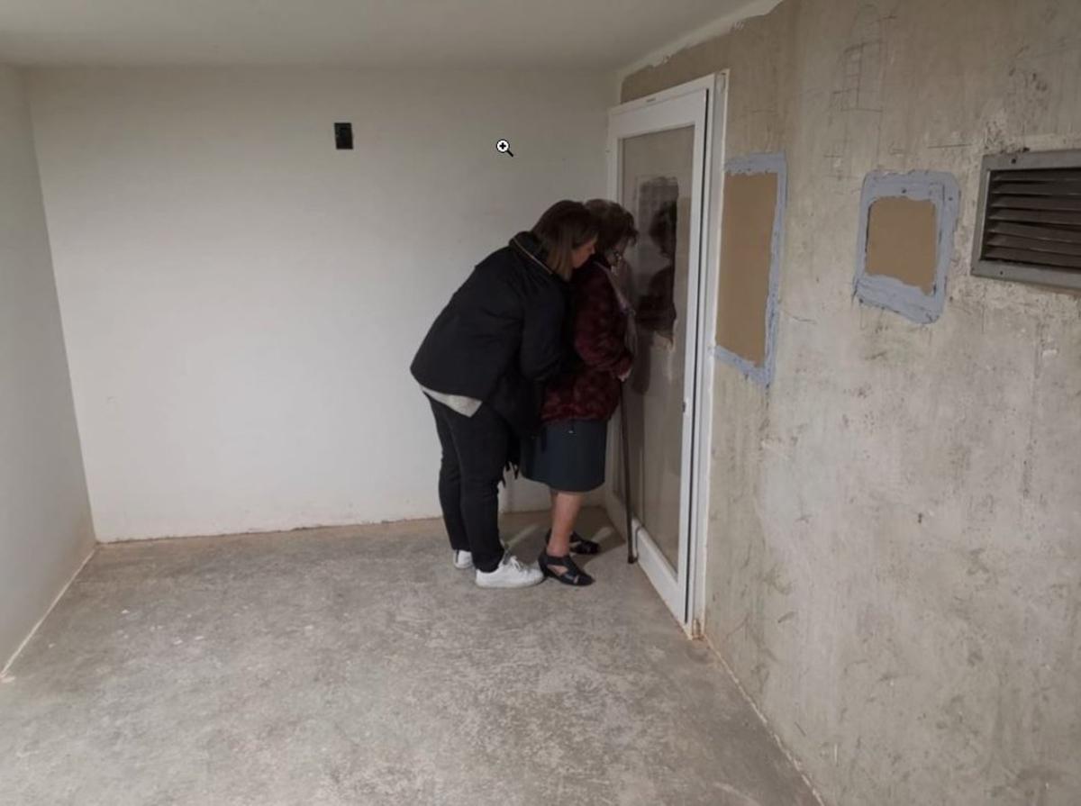 Emocionadas, dos familiares se asoman al agujero practicado en la pared de la cripta del Valle de los Caídos.