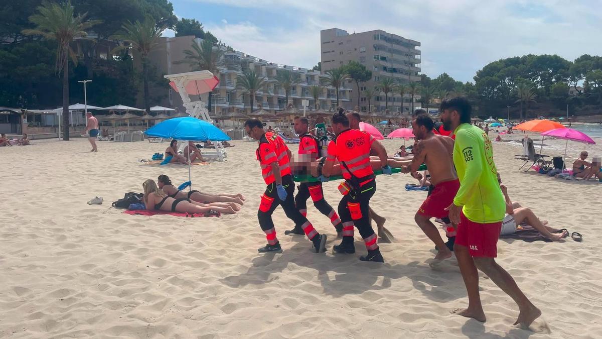 Socorristas y personal sanitario trasladan a la ambulancia al turista portugués rescatado en Peguera con síntomas de ahogamiento.