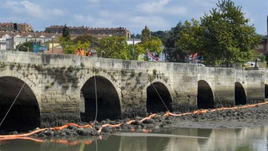 Barrera colocada en el puente de O Burgo para contener el vertido de queroseno. / fran martínez