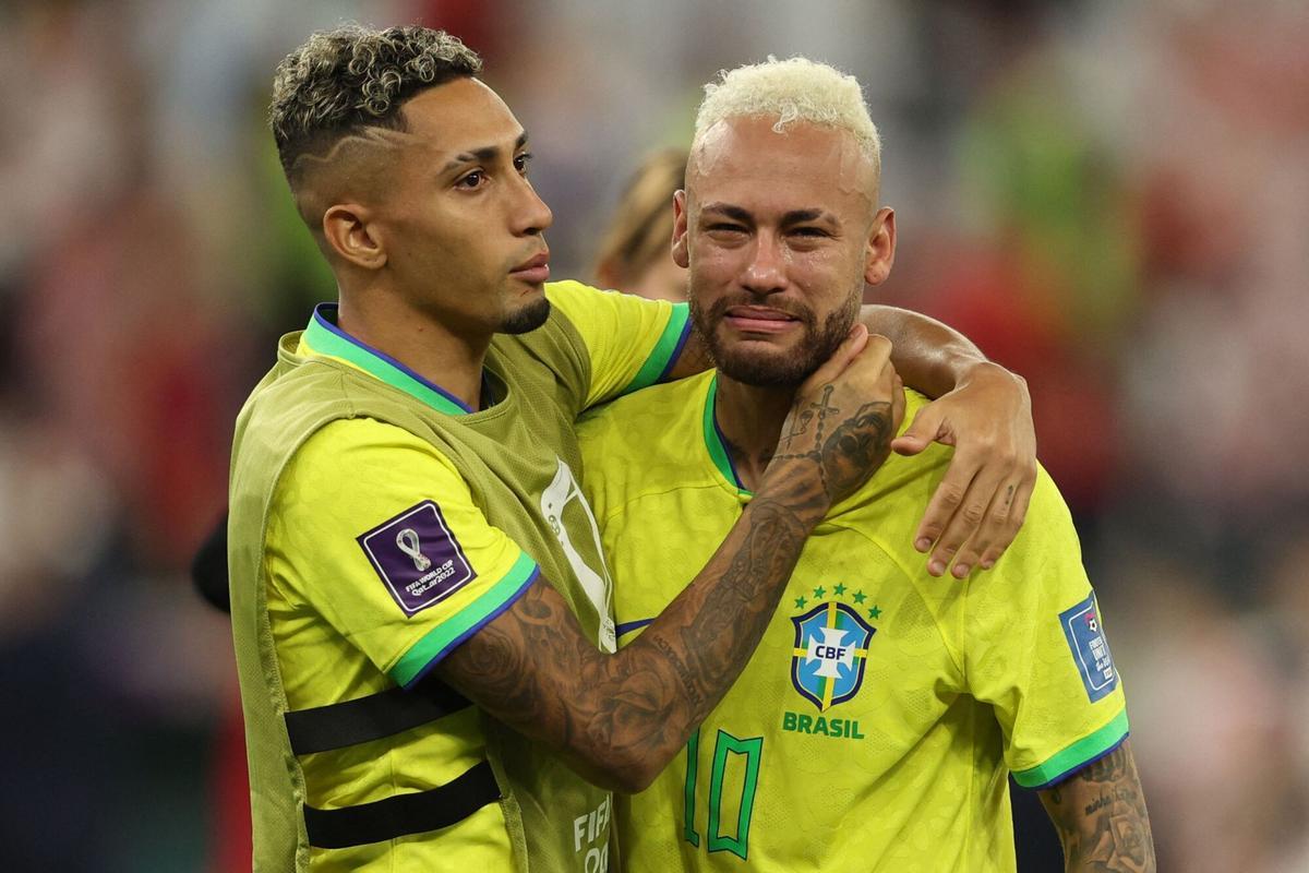 El delantero brasileño #10 Neymar (R) es consolado por el delantero brasileño #11 Raphinha después de que su equipo perdiera el partido de fútbol de cuartos de final de la Copa Mundial Qatar 2022 entre Croacia y Brasil en el Education City Stadium de Al-Rayyan, al oeste de Doha, el 9 de diciembre de 2022. (Foto de Adrian DENNIS / AFP)