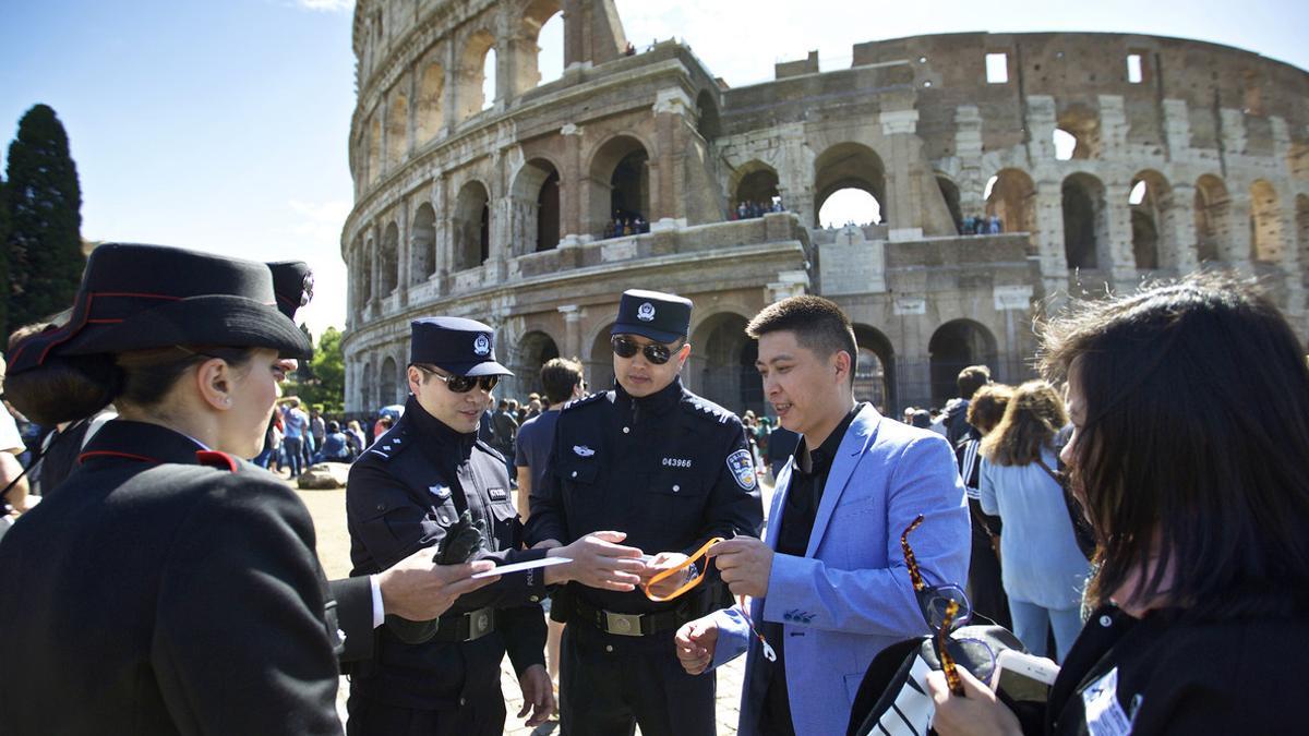 Dos agentes chinos, junto a dos italianos, revisan la documentación de un grupo de turistas chinos, en el exterior del Coliseo, en Roma, este lunes.