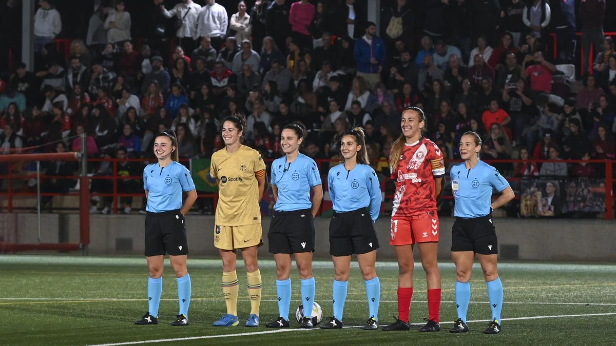 Las capitanas y el conjunto arbitral se fotografían antes del partido aplazado de la primera jornada de la liga de fútbol femenino entre el Levante Las Planas y el FC Barcelona.