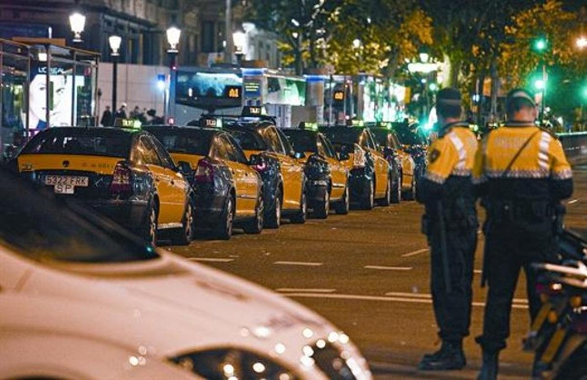 Cua de taxis i una patrulla de la Guàrdia Urbana, dilluns a la nit en una de les parades de la plaça de Catalunya. Cua de taxis i una patrulla de la Guàrdia Urbana, dilluns a la nit en una de les parades de la plaça de Catalunya.