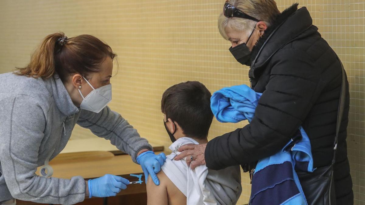 Un alumno recibe la primera dosis de su vacuna en un colegio de València acompañado por un familiar el pasado diciembre. | F.CALABUIG
