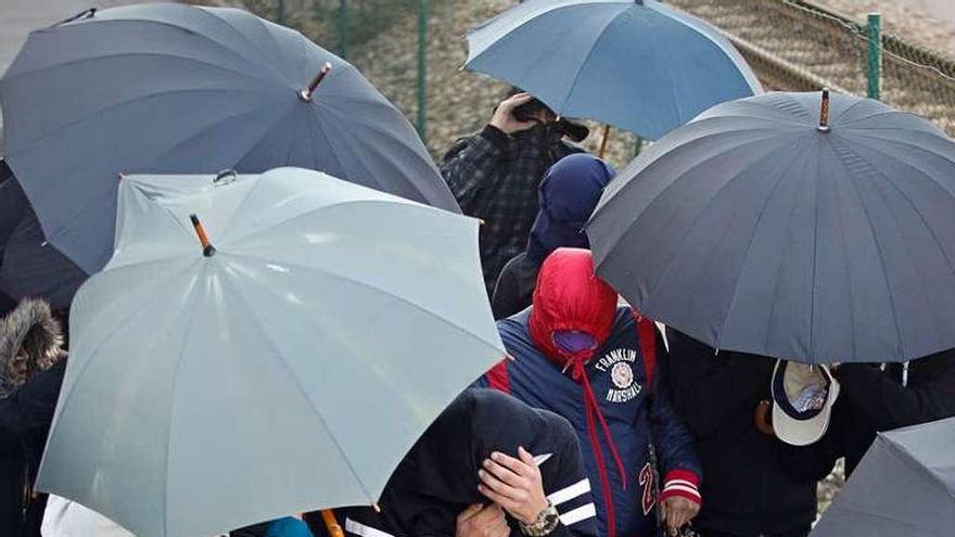 Un grupo de mujeres utiliza unos paraguas para proteger a sus amigos detenidos a la salida de los calabozos del Juzgado.