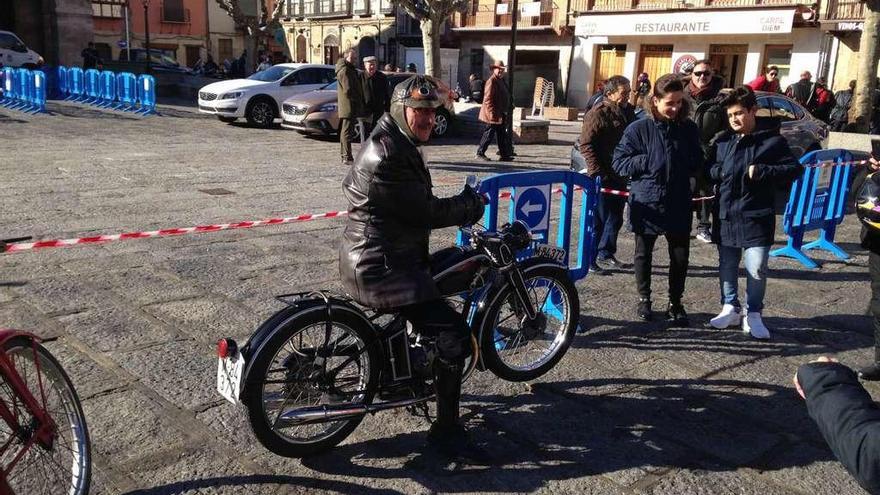 El motero Andrés Zarzuela posa sobre su vieja moto, ayer en Toro, ante un grupo de jóvenes interesados en ver el vehículo .