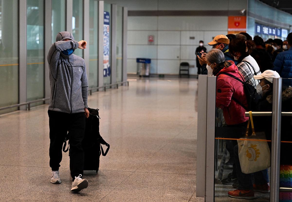 Un pasajero se cubre la cara en el área de llegadas de vuelos internacionales en el Aeropuerto Internacional de la Capital en Beijing.