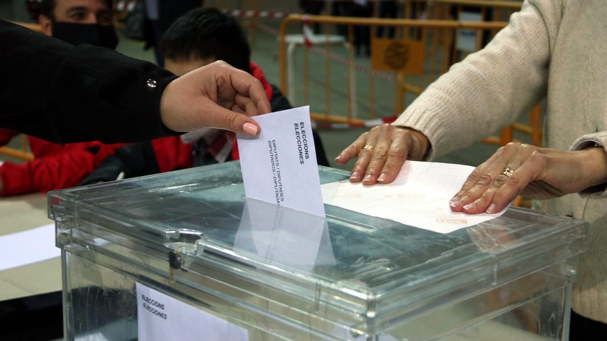 Una persona deposita el voto en la urna en las elecciones del 14-F