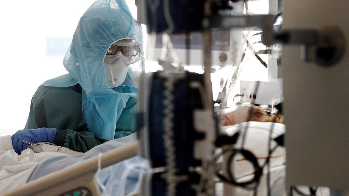 Sanitaria atiende a paciente en el interior de la UCI de un hospital.