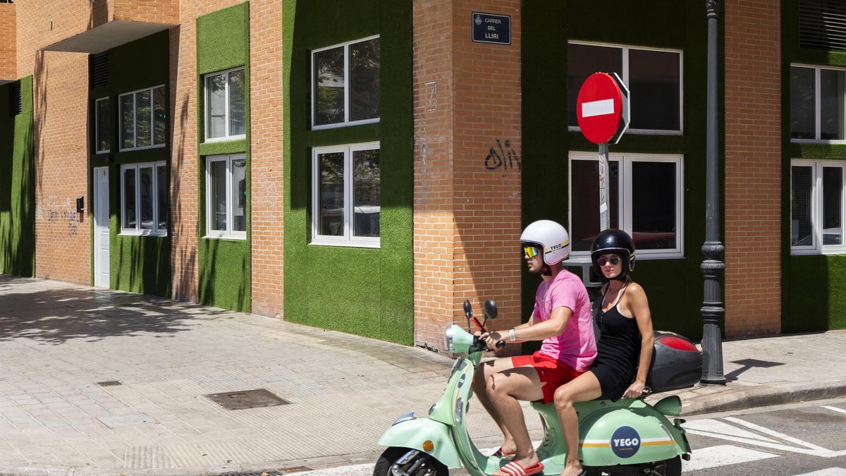 Una pareja en moto pasa por delante de unos pisos turísticos en la calle Juan Verdeguer.