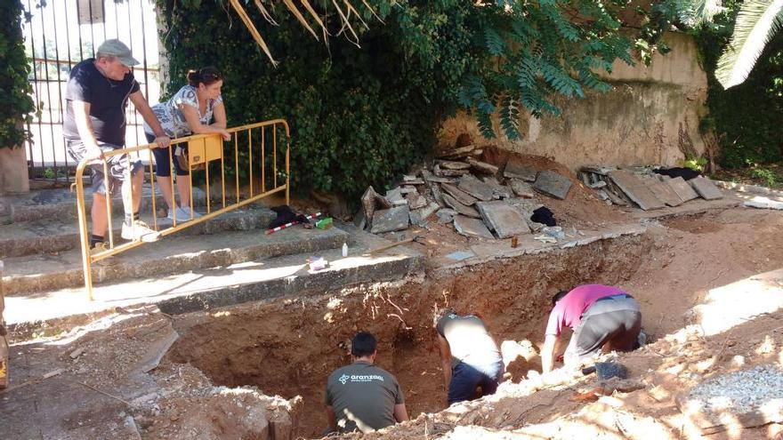 Dos personas observan a varios operarios durantre las labores de excavación de la supesta fosa.