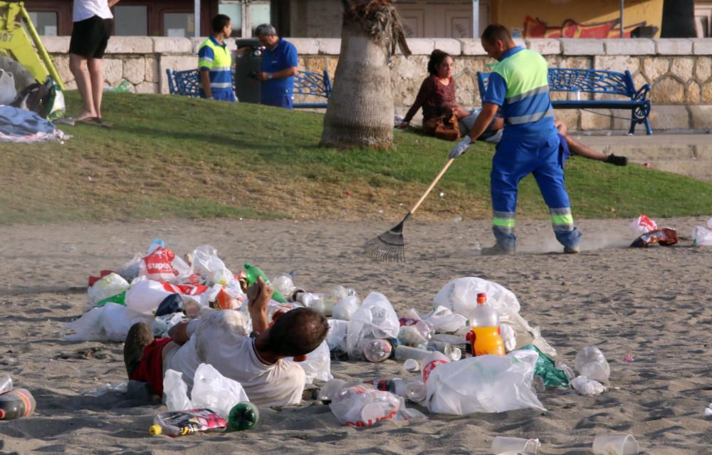 Los operarios de los servicios de limpieza trabajan para dejar la playa en óptimas condiciones tras una larga noche de fiesta en la arena