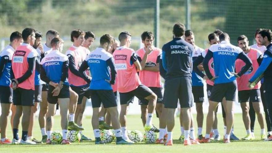 Los futbolistas del Deportivo atienden las explicaciones de Víctor Sánchez sobre el césped de Abegondo.