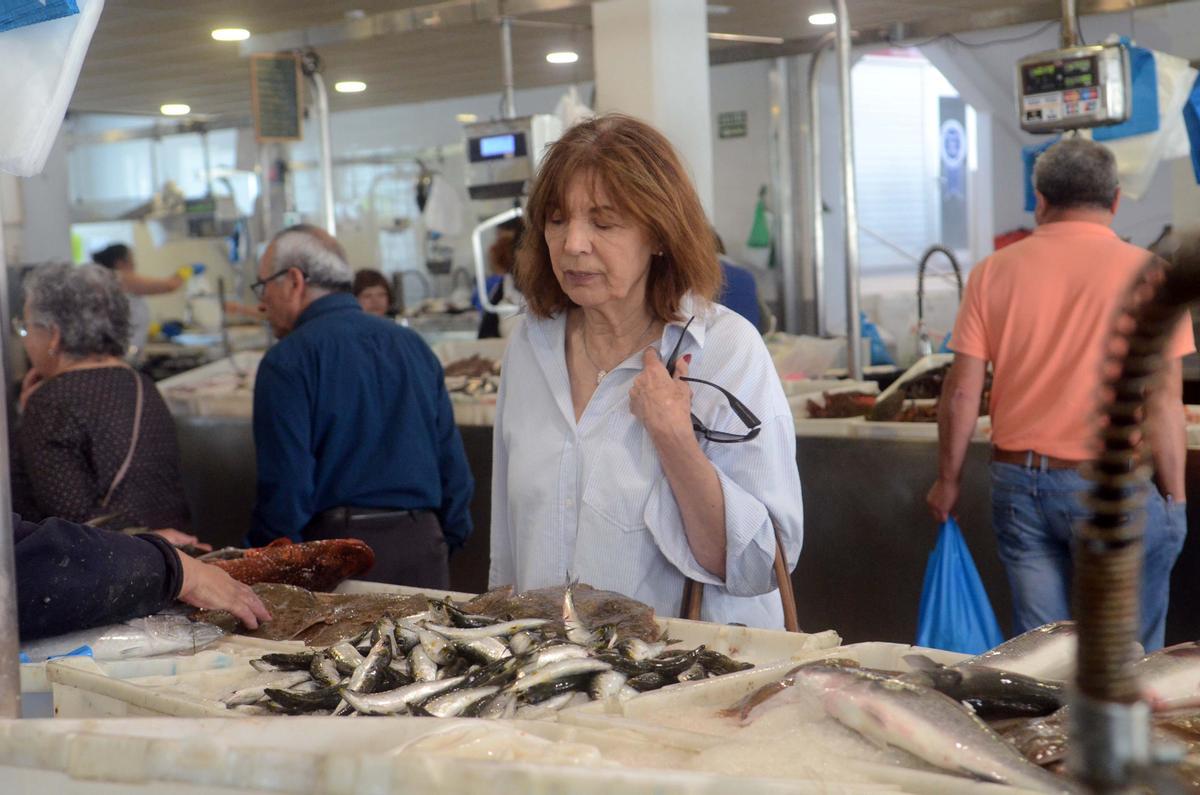 Una mujer observa un puesto de pescado.