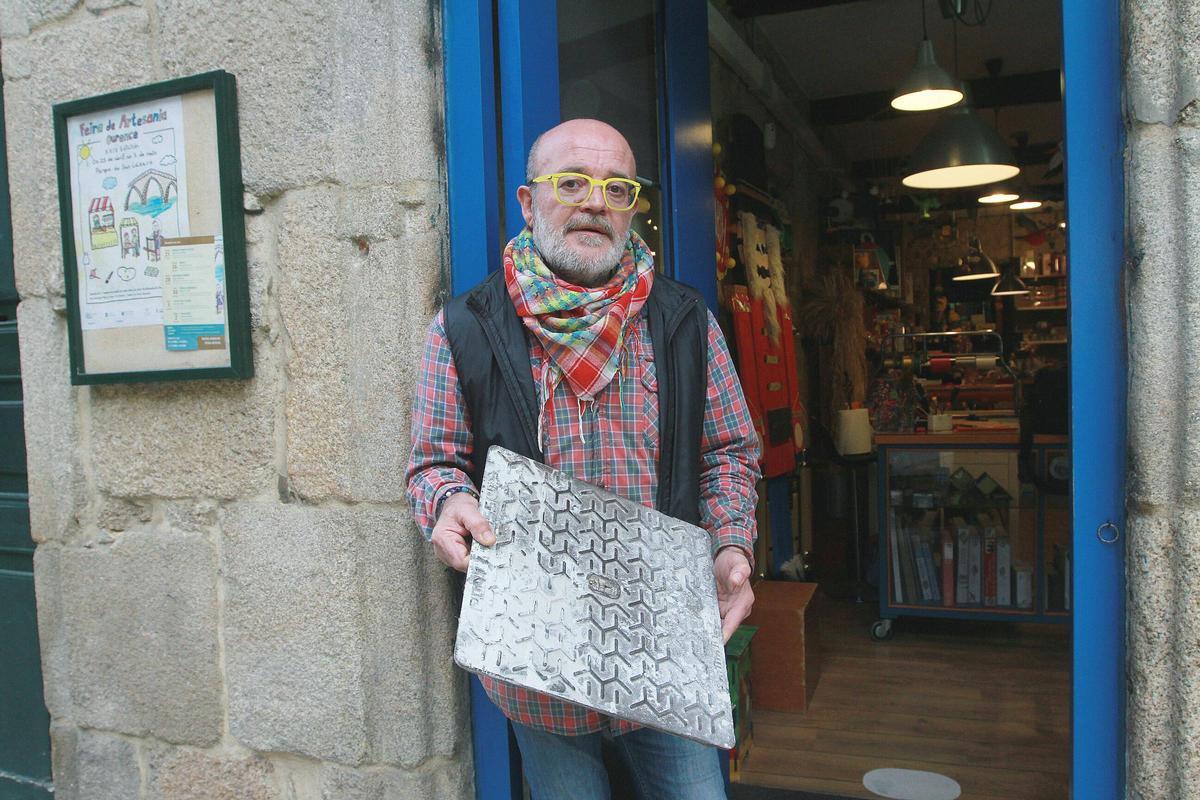 Carlos Rodríguez a las puertas de su tienda, A Bufarda, mostrando la arqueta empleada en el robo.