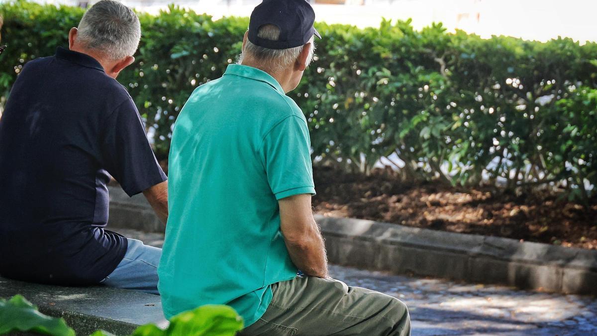 Dos personas mayores sentadas en un banco.