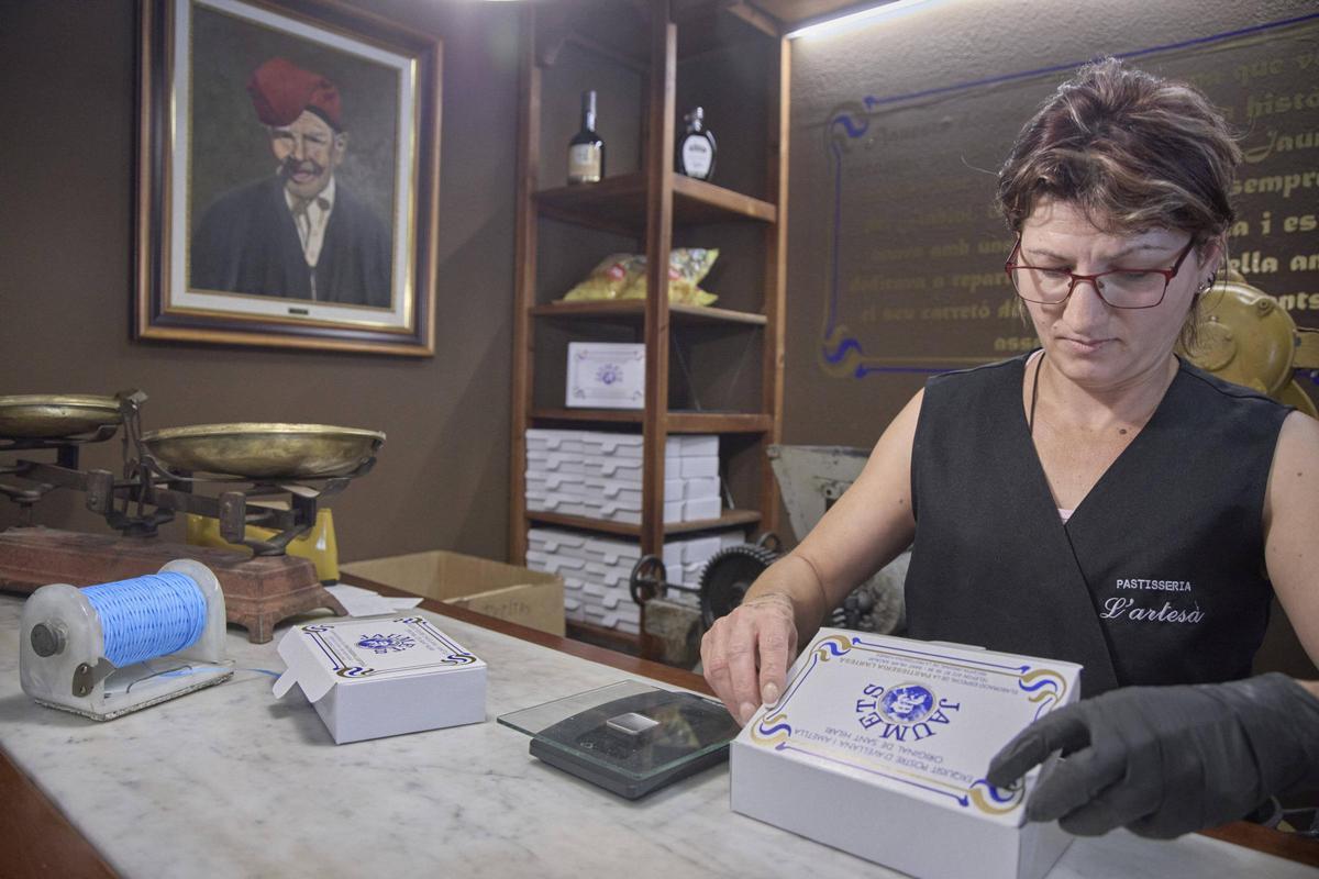 Una dependenta de la pastisseria l'Artesà preparant caixes de jaumets.