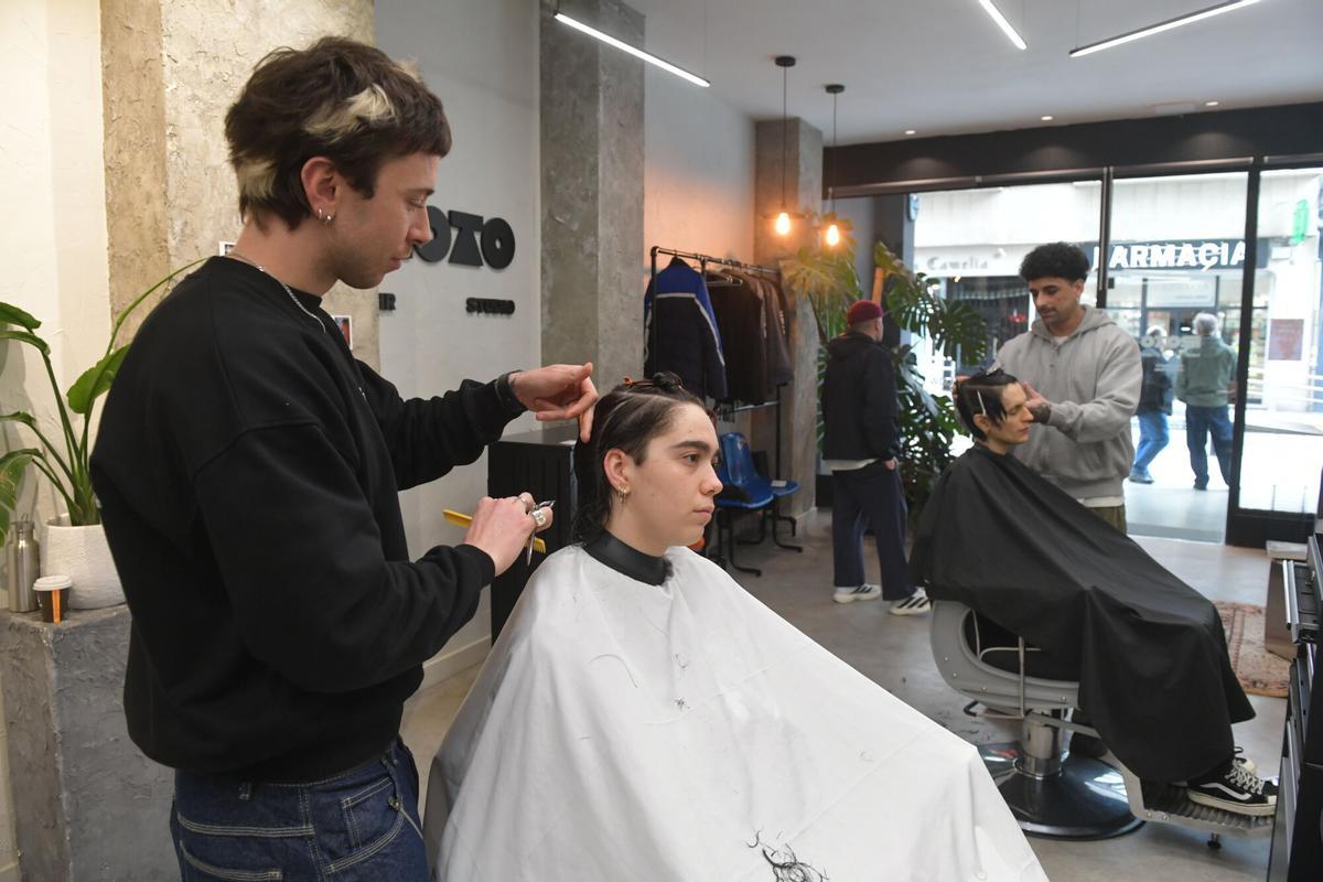 Los peluqueros de Roto Studio cortan el pelo a dos clientes.