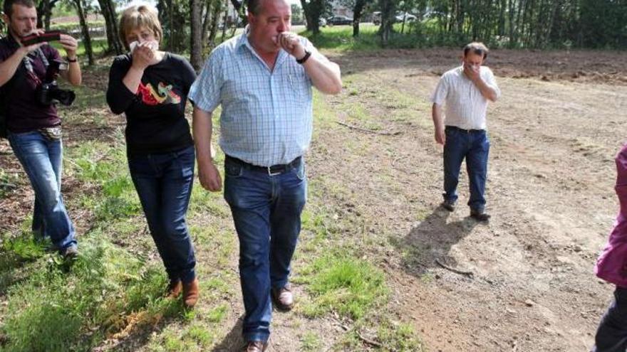 Vecinos se cubren con pañuelos la nariz mientras muestran una de las fincas a un edil (centro). / bernabé / luismy