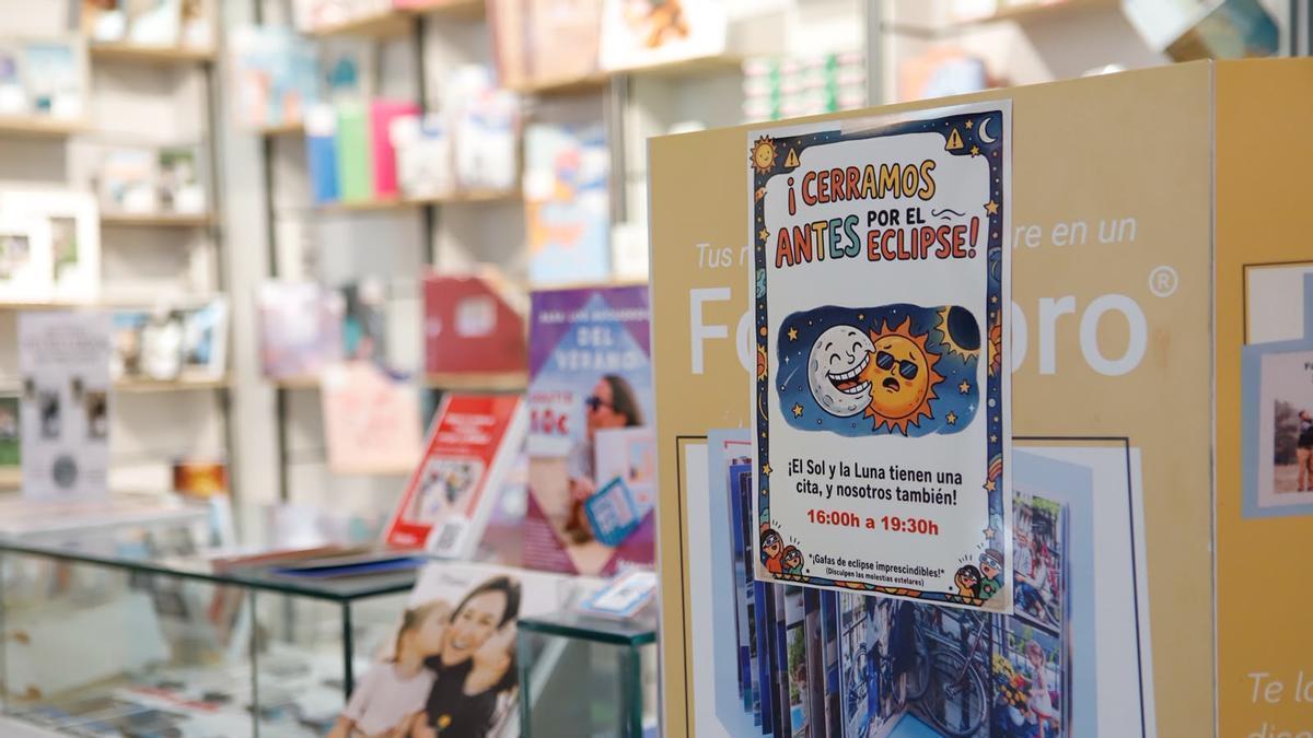Cartel anunciando el adelanto del cierre en la jornada del eclipse en una tienda de Fotoprix de Zaragoza.