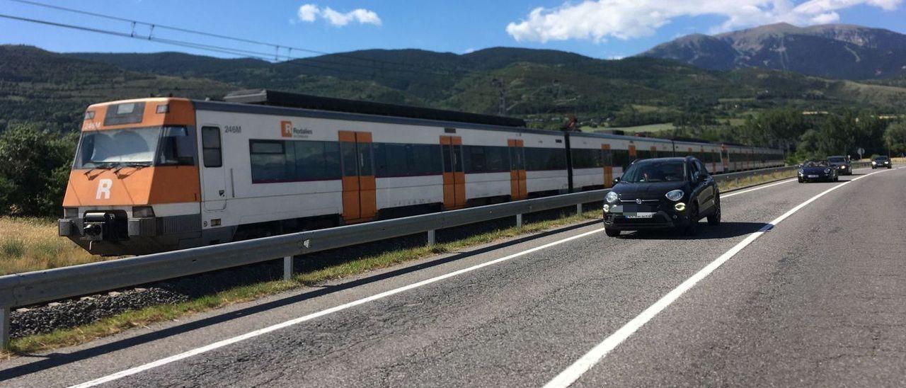 Un tren de la línia R3 circula a la recta d’entrada a Puigcerdà en el tram del trajecte que transcorre paral·lel a la carretera N-260 entre la Molina, al fons, i la vall