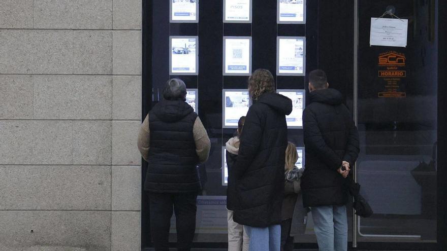 Varias personas ojean pisos en alquiler en el escaparate de una inmobiliaria. | Antonio Hernández