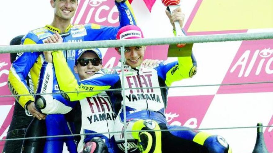 Lorenzo, sentado en el podio debido a sus fracturas en los tobillos, por delante de Edwards y con Rossi en sus rodillas.