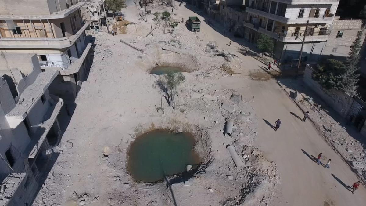 A still image taken on September 27, 2016 from a drone footage obtained by Reuters shows people standing near craters and damaged buildings in a rebel-held area of Aleppo