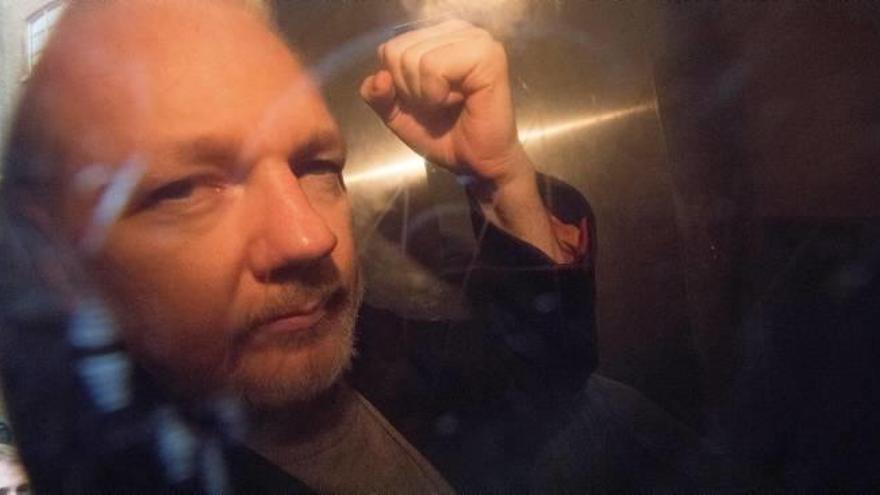 Assange saluda al salir detenido de la embajada ecuatoriana en Londres el 11 de abril.